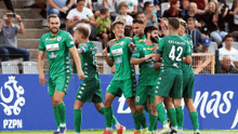 a group of soccer players wearing green uniforms with the number 42 on their backs