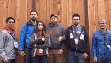 a group of people standing in front of a wooden wall with one man wearing a lanyard that says ' acorn '