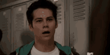 a young man with a surprised look on his face is standing in front of lockers in a locker room .