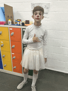 a boy dressed as a clown giving a thumbs up in front of a sign that says pino