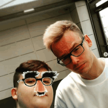 a man wearing glasses stands next to another man with a fake nose on his face