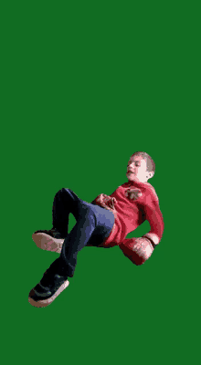 a young boy wearing a red spiderman shirt is laying on his back on a green background