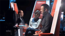 a man is sitting in a chair with a microphone in his mouth while a woman sits next to him