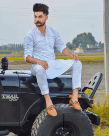 a man sits on the hood of a thar crd