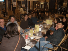 a group of people sitting around a table in a restaurant with a sign that says ' avenida ' on it