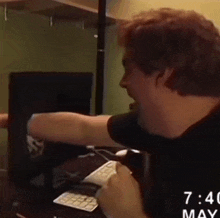 a man is sitting at a desk with a keyboard and a monitor and the time is 7:40