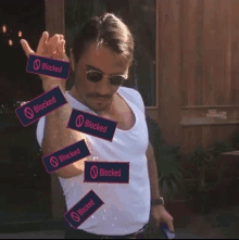 a man wearing sunglasses and a white shirt has a bunch of blocks that say blocked