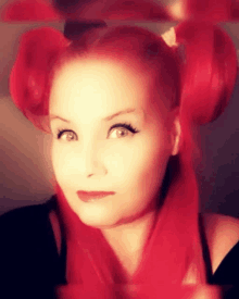 a woman with red hair and pigtails is looking at the camera in front of a mirror .