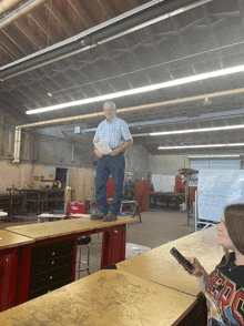 a man in a plaid shirt stands on a table while a girl looks on