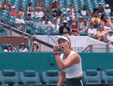 a tennis player holds her fist up in the air in front of a crowd of people sitting in a stadium with the number 148 visible