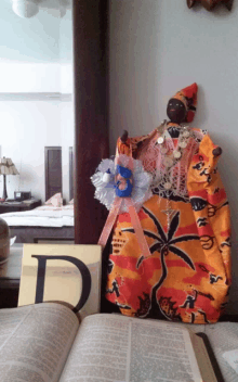 a doll is sitting on a table next to an open bible