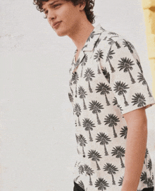 a man in a white shirt with black palm trees on it