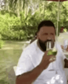 a man with a beard is drinking a glass of wine outside .