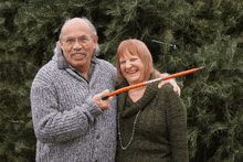 a man and a woman are posing for a picture and the woman is holding a pencil