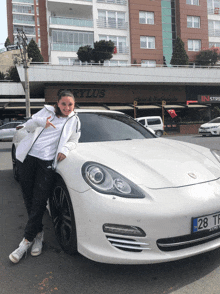 a girl stands in front of a white car with a license plate that says 28 tl