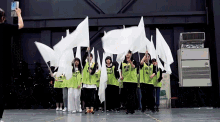 a group of people holding up white flags with one wearing a green shirt that says " i feel alive "