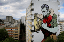 a mural on the side of a building shows a man and woman hugging each other