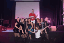 a group of people posing for a picture with a man wearing a red shirt that says shark teeth