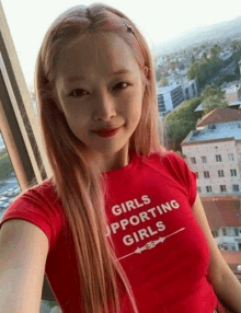 a woman wearing a red t-shirt that says girls supporting girls