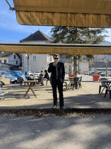 a man in a suit and sunglasses stands under a canopy