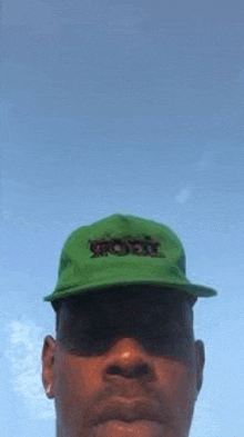 a man is wearing a green hat and sunglasses .