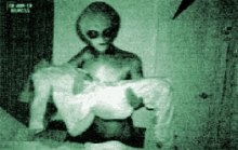 a black and white photo of an alien holding a baby in his arms .