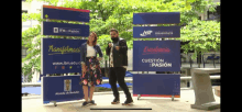 a man and a woman are dancing in front of a sign that says jtm