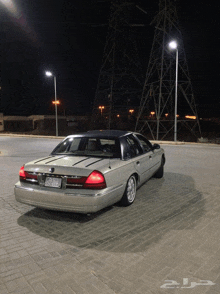 a silver car is parked on a brick pavement in front of a power line