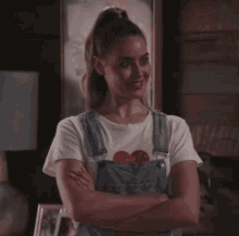 a woman wearing overalls and a white t-shirt with a red heart that says " i love you "