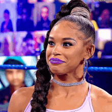 a woman with purple lipstick and a braided ponytail is smiling