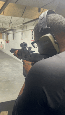 a man wearing a pair of ear defenders is aiming a gun at a target with the number 5 on it