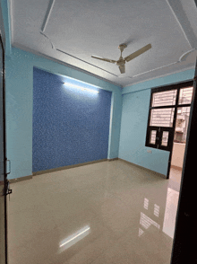 an empty room with a ceiling fan and a blue wall