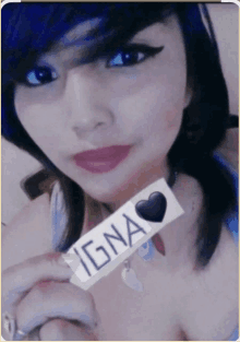 a girl with blue hair holds up a sticker that says igna