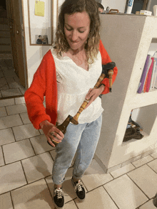 a woman wearing a red sweater and a white shirt is holding a pipe