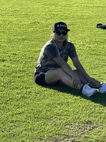 a woman sits on the grass wearing a chilla hat