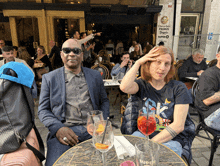 a man in a suit sits at a table in front of a sign that says super