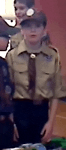 a boy in a scout uniform is standing in front of a table