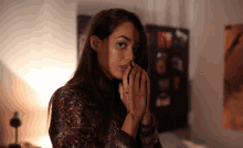 a woman covering her face with her hands in front of a wall with pictures