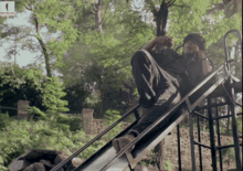 a man is sitting on a slide and talking on a cell phone with a picture of a woman behind him