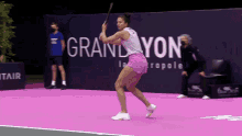 a woman is swinging a tennis racket on a court with a sign that says grand yon in the background