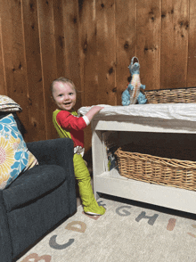 a little boy standing next to a couch and a table with the letters g h and i on it