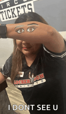 a woman wearing a locker room haircuts shirt is covering her face