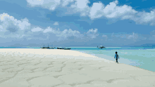 a boy walking on a beach with boats in the background