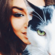 a woman is taking a selfie with half of her face covered by a black and white cat .