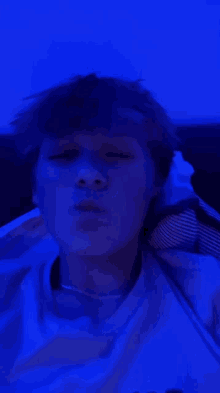 a young man is blowing a kiss in front of a blue background .