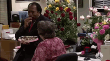 a man in a suit and tie is holding a cake in front of a woman in a pink dress