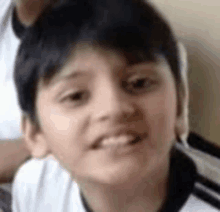 a close up of a young boy 's face with a white shirt on .