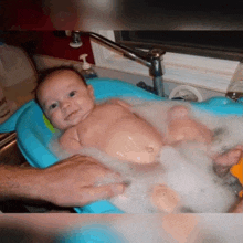 a baby is taking a bath in a bathtub with foam