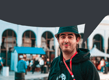 a man wearing a black hat and a black hoodie stands in front of a building