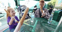 a man and a little girl are eating churros at a table with a bottle of aquafina water on it